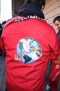 Este aficionado del Extremadura lleva una cigüeña serigrafiada en el chaquetón porque es uno de los mayores símbolos de esta comunidad autónoma.